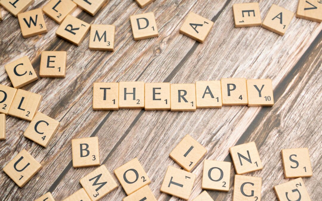 Fichas de Scrabble formando la palabra "Therapy" sobre una mesa de madera, representando el concepto de terapia en el contexto de psicoanálisis y psicoterapia.